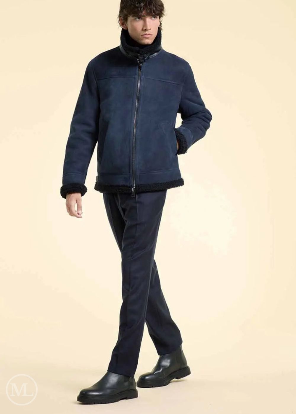 Man wearing a navy blue suede jacket, pants, and shoes on a beige background