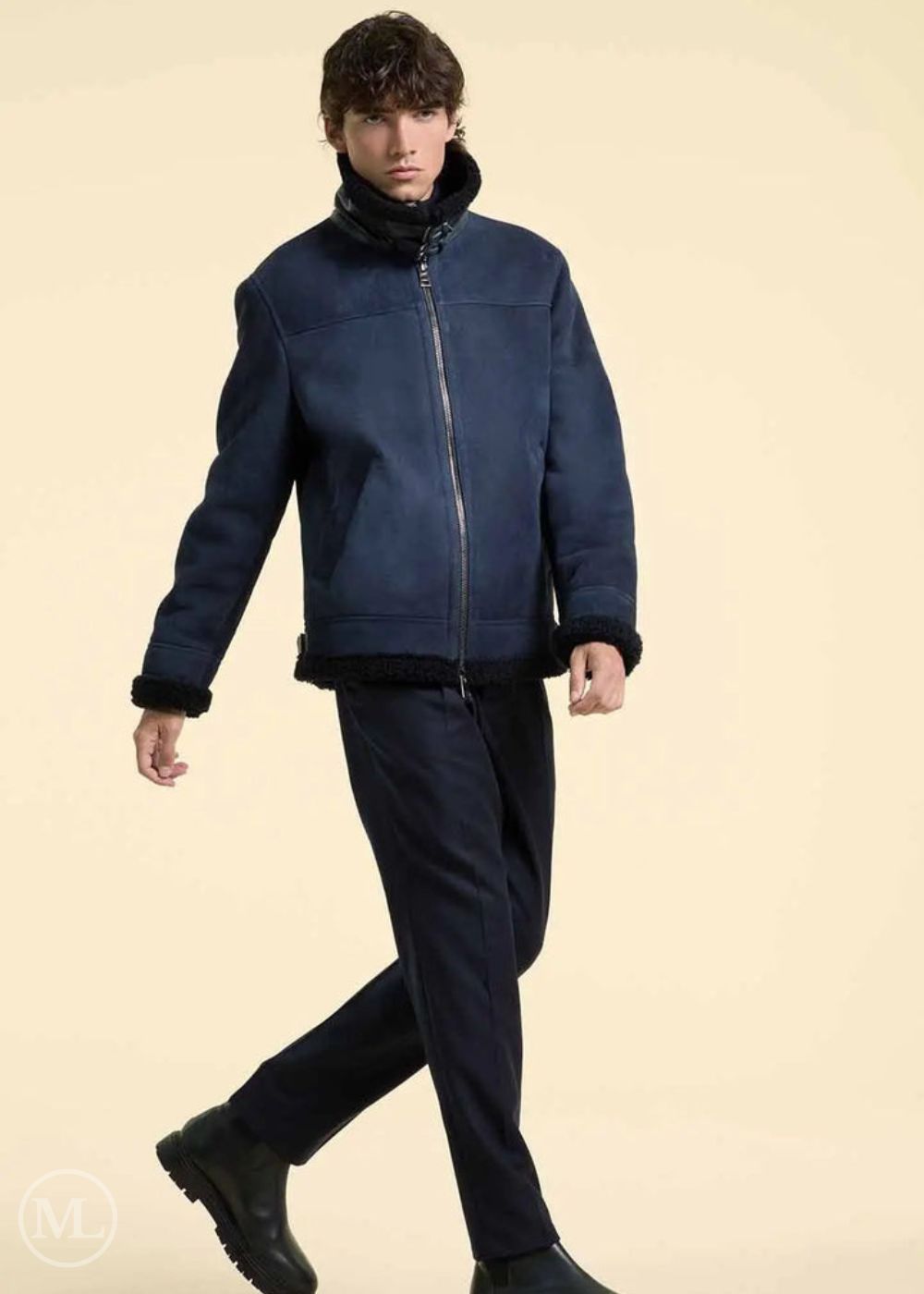 Man wearing a navy blue suede jacket and black pants on a beige background