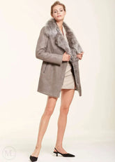 Woman wearing a grey leather coat with fur collar on a white background