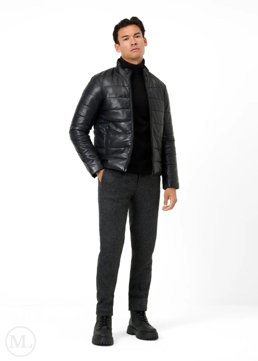 Man wearing a black leather puffer jacket, black turtleneck, gray pants, and black shoes on a white background