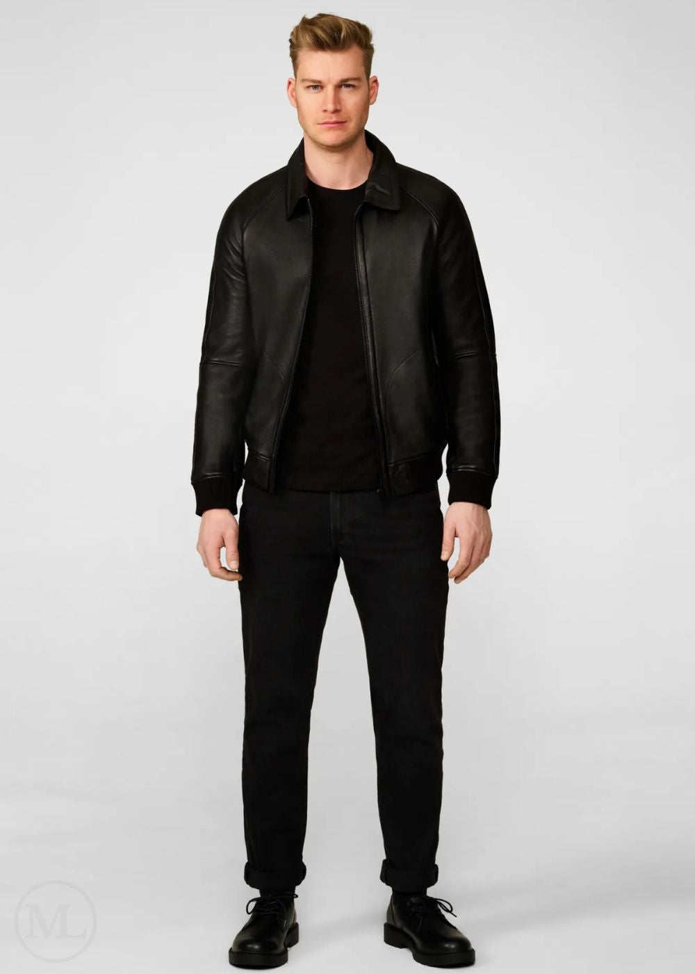 Man wearing a black leather bomber jacket and black pants on a white background