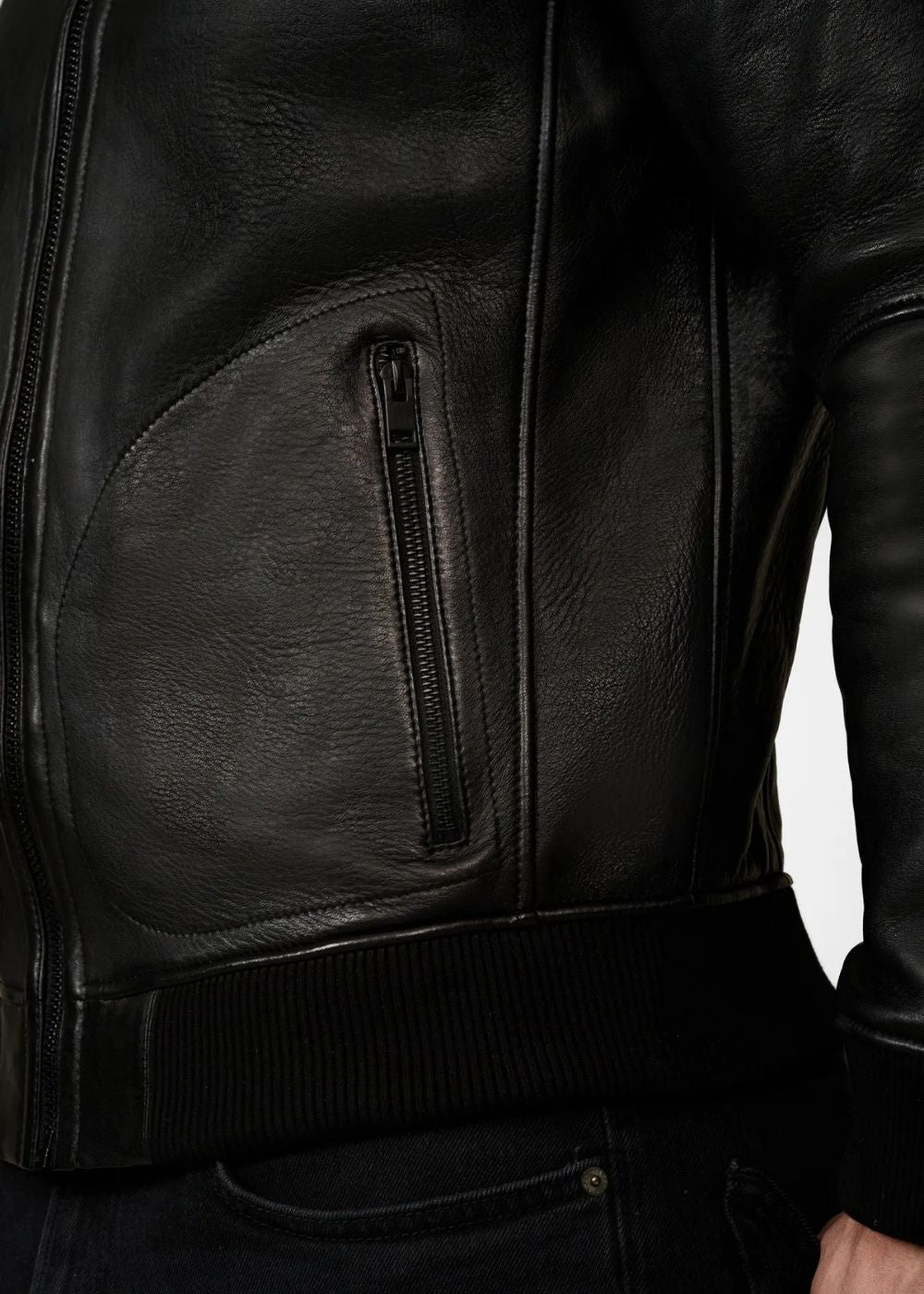 Close-up of a black leather bomber jacket with a zipper pocket worn by a man on a white background