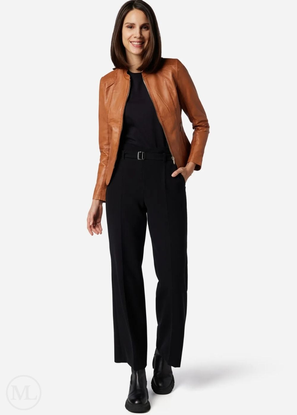 Woman wearing a cognac brown leather jacket and black pants on a white background