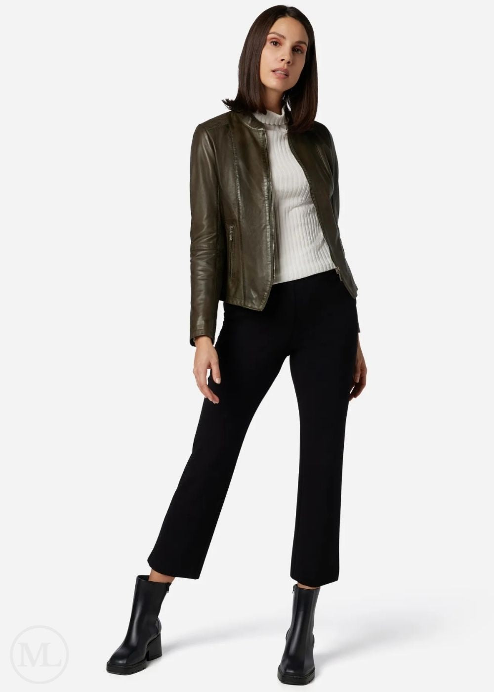 Woman wearing a olive green leather jacket, white turtleneck, black pants, and black boots on a white background