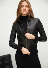 Woman wearing a black leather bomber jacket against a white background