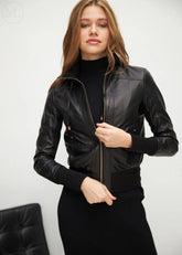 Woman wearing a black leather bomber jacket against a white background