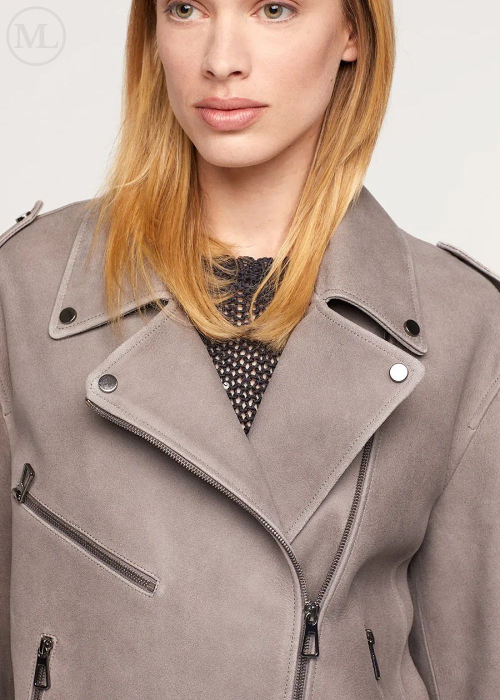Close-up of a woman wearing a gray nebuck leather biker jacket with a neutral background