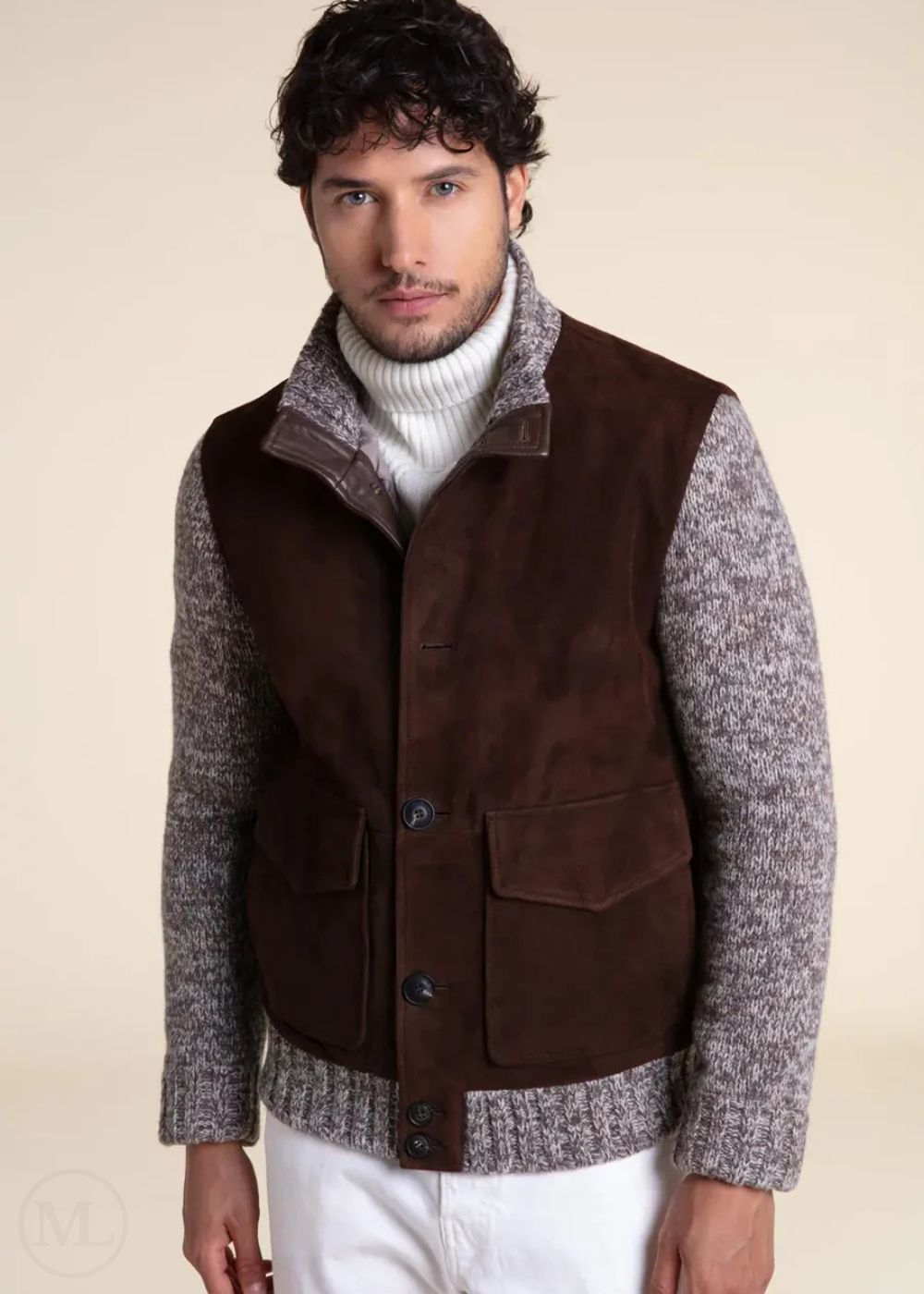 Man wearing a dark brown jacket over a gray sweater with a beige background