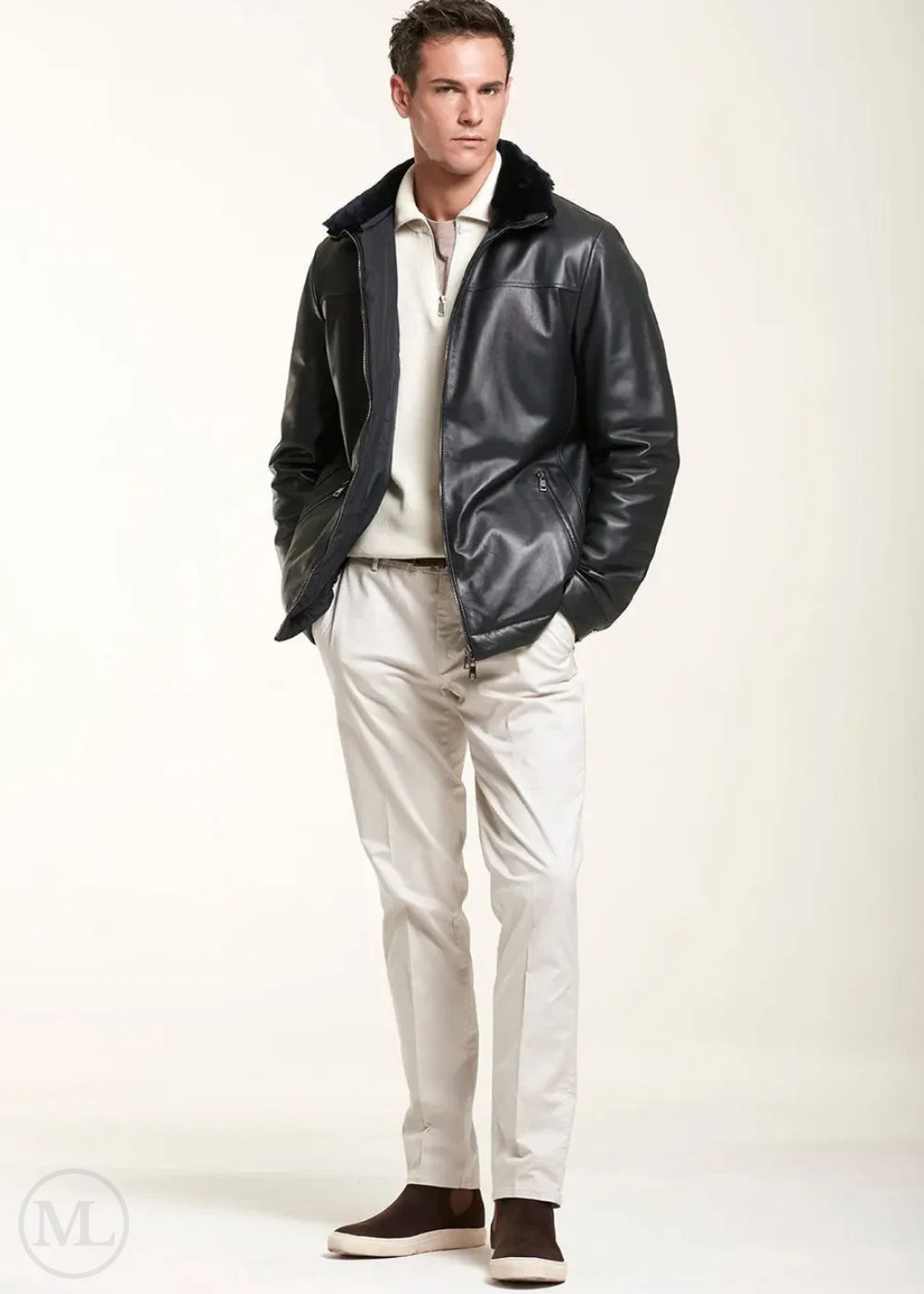 Homme portant une veste en cuir noire sur une chemise et un pantalon blancs sur fond blanc