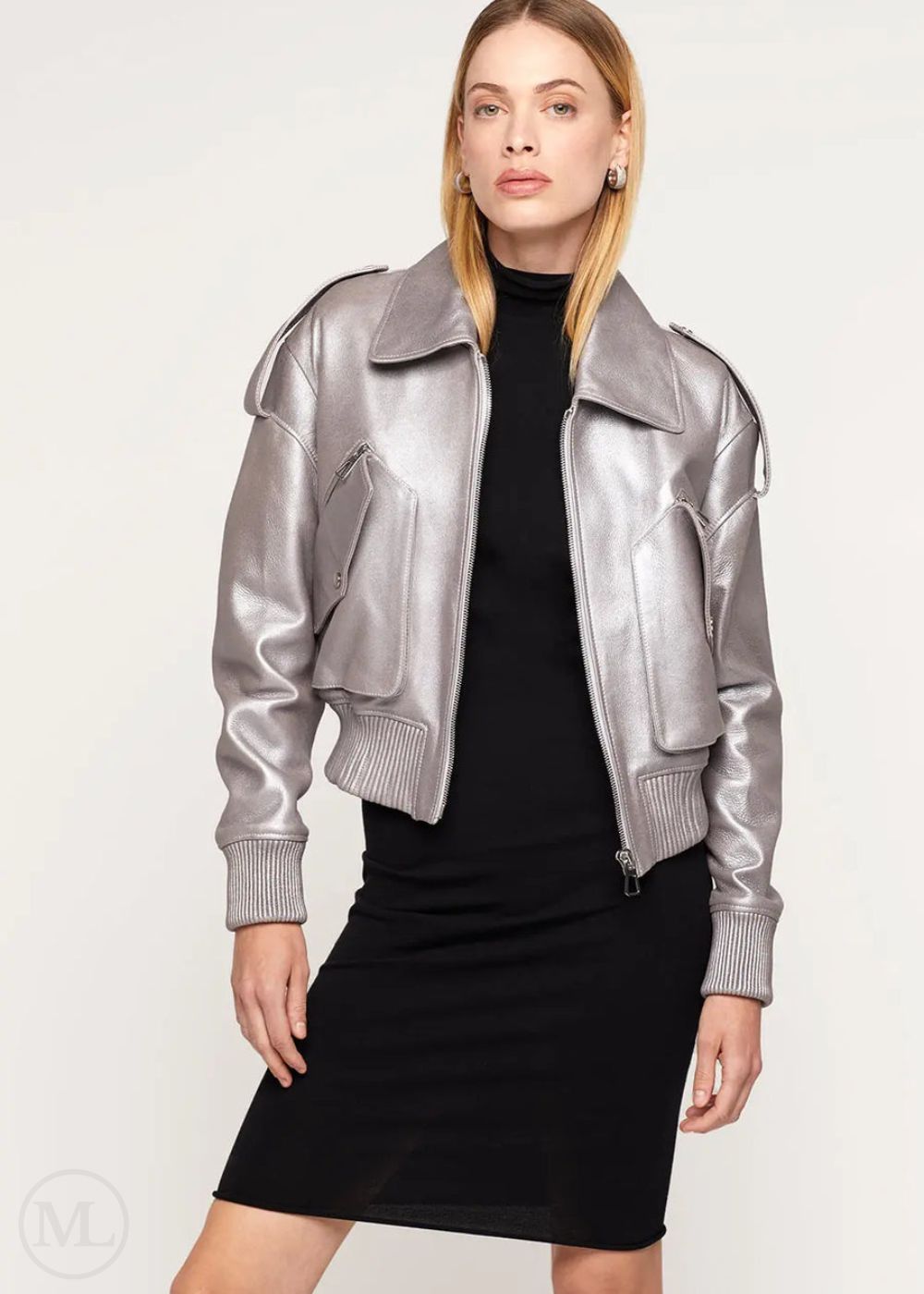 Woman wearing a silver leather bomber jacket over a black dress on a white background
