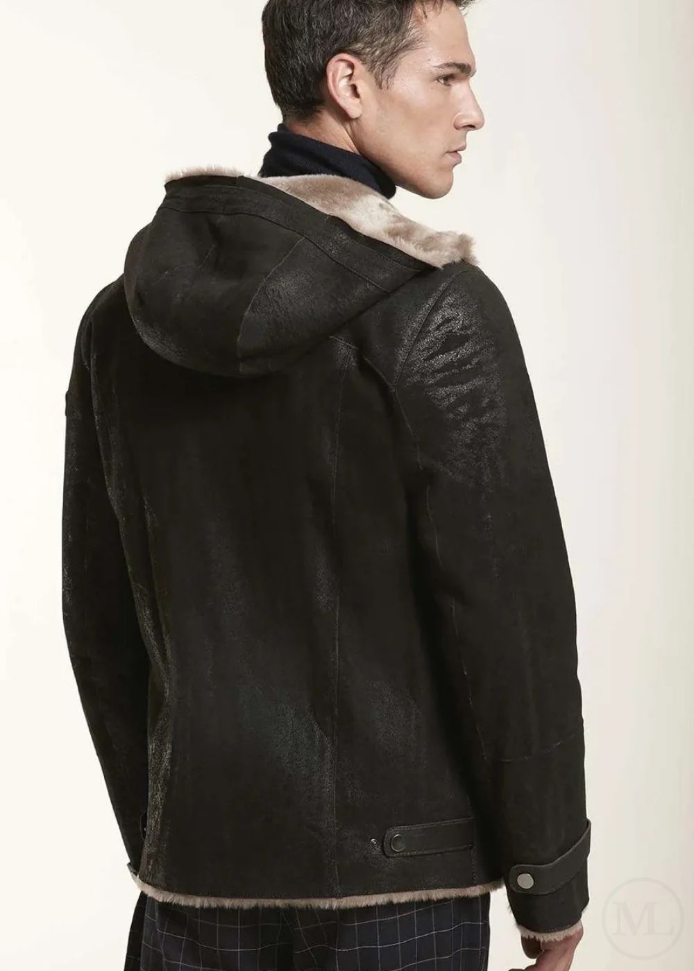 Man wearing a dark brown leather jacket with fur lining on a plain background