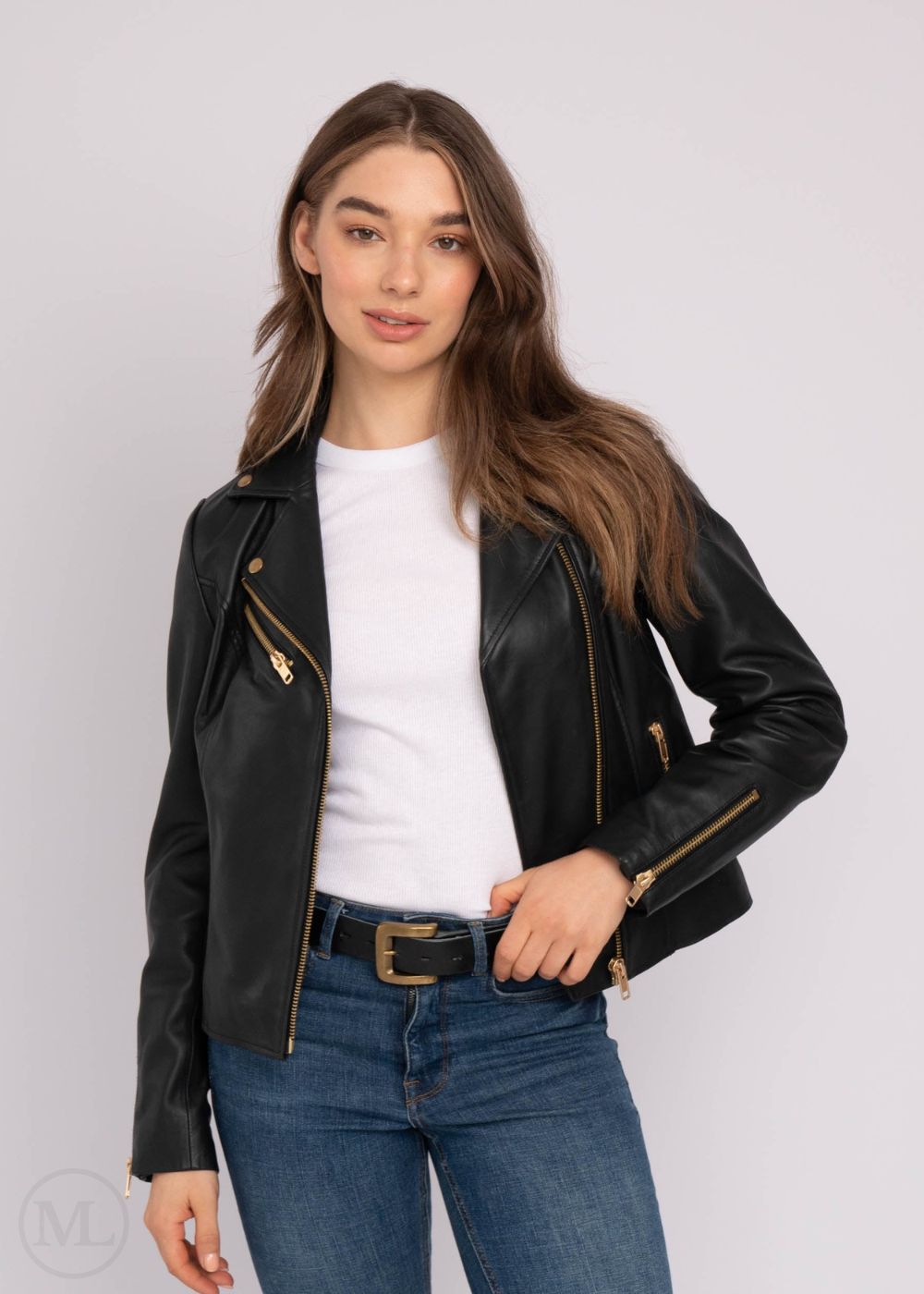Woman wearing a black leather biker jacket, white shirt, and blue jeans on a plain background