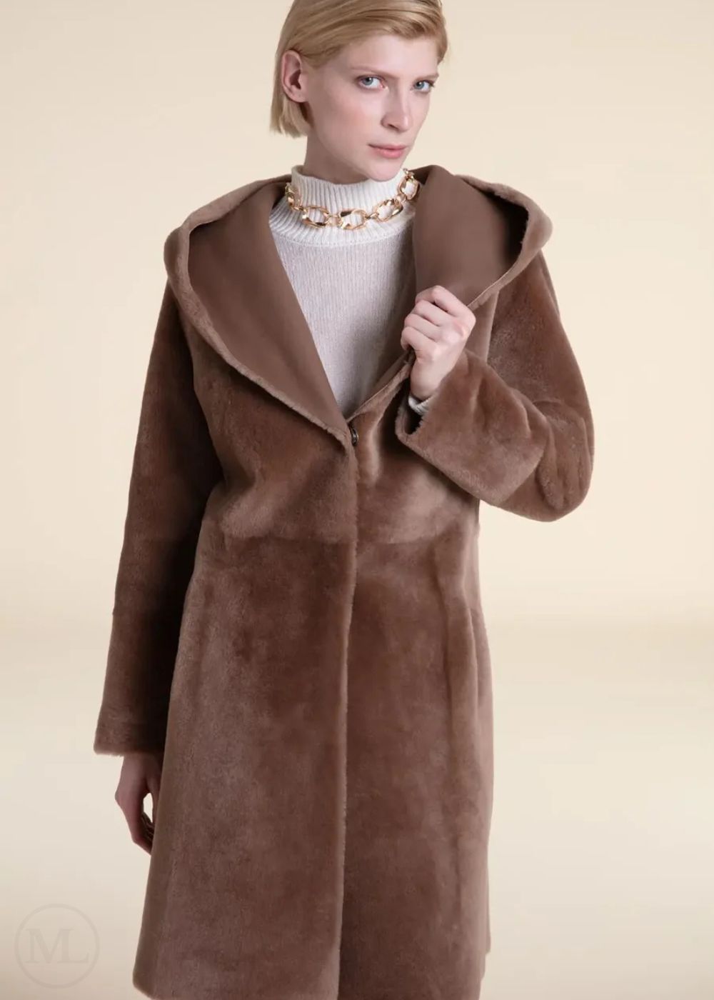 Woman wearing a beige shearling leather coat against a beige background