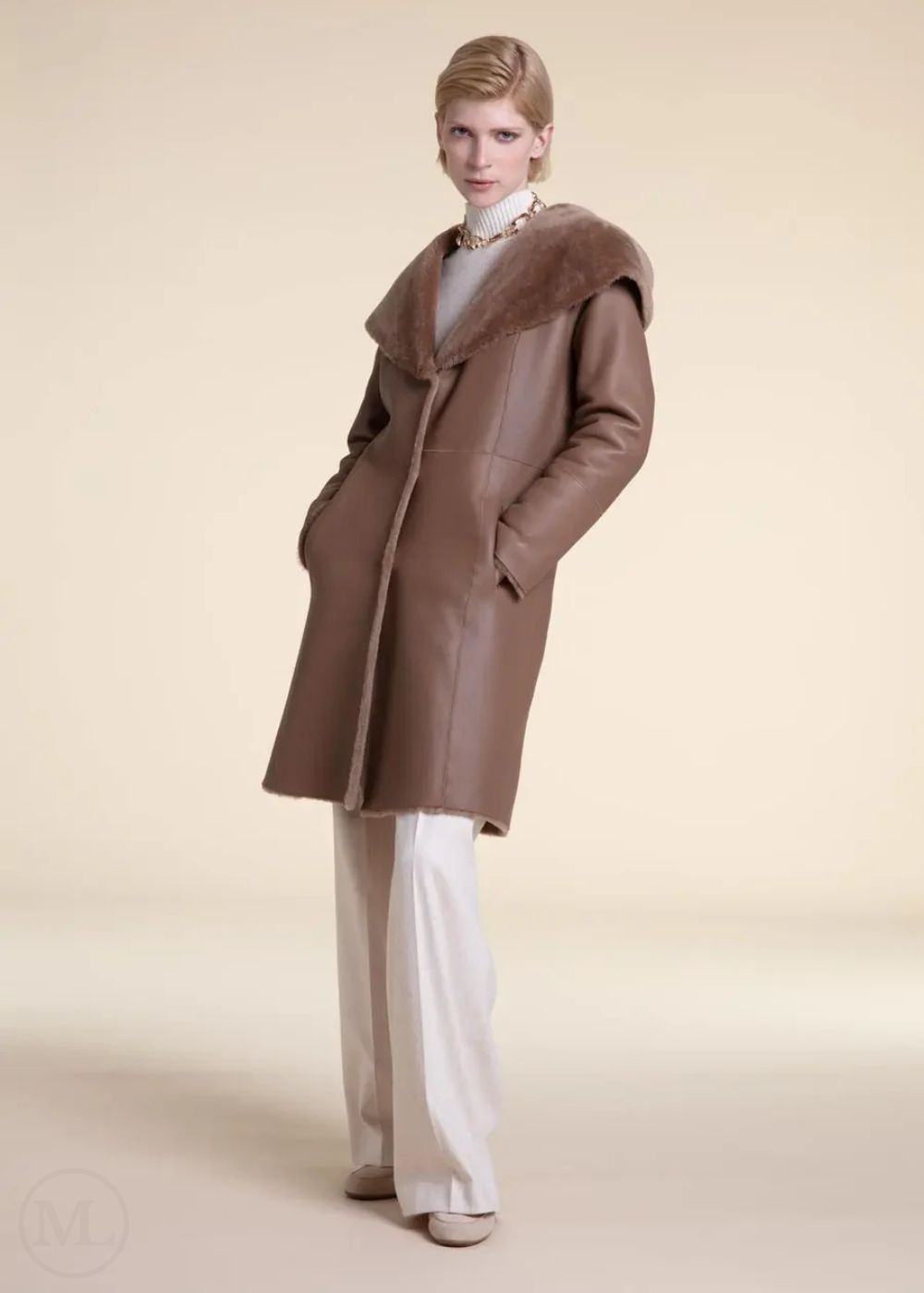 Woman wearing a beige shearling leather coat with fur collar on a beige background
