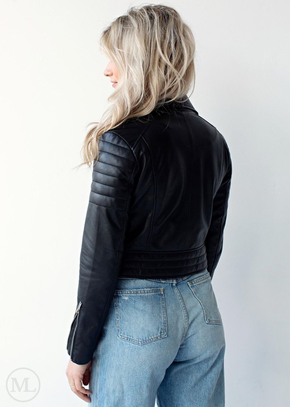 Women wearing a black leather biker jacket and blue jeans on a white background
