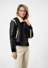 Woman wearing a black leather aviator jacket with beige interior and trim on a white background