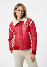 Woman wearing a red leather aviator jacket with white trim on a white background