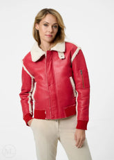 Woman wearing a red leather aviator jacket with white trim on a white background