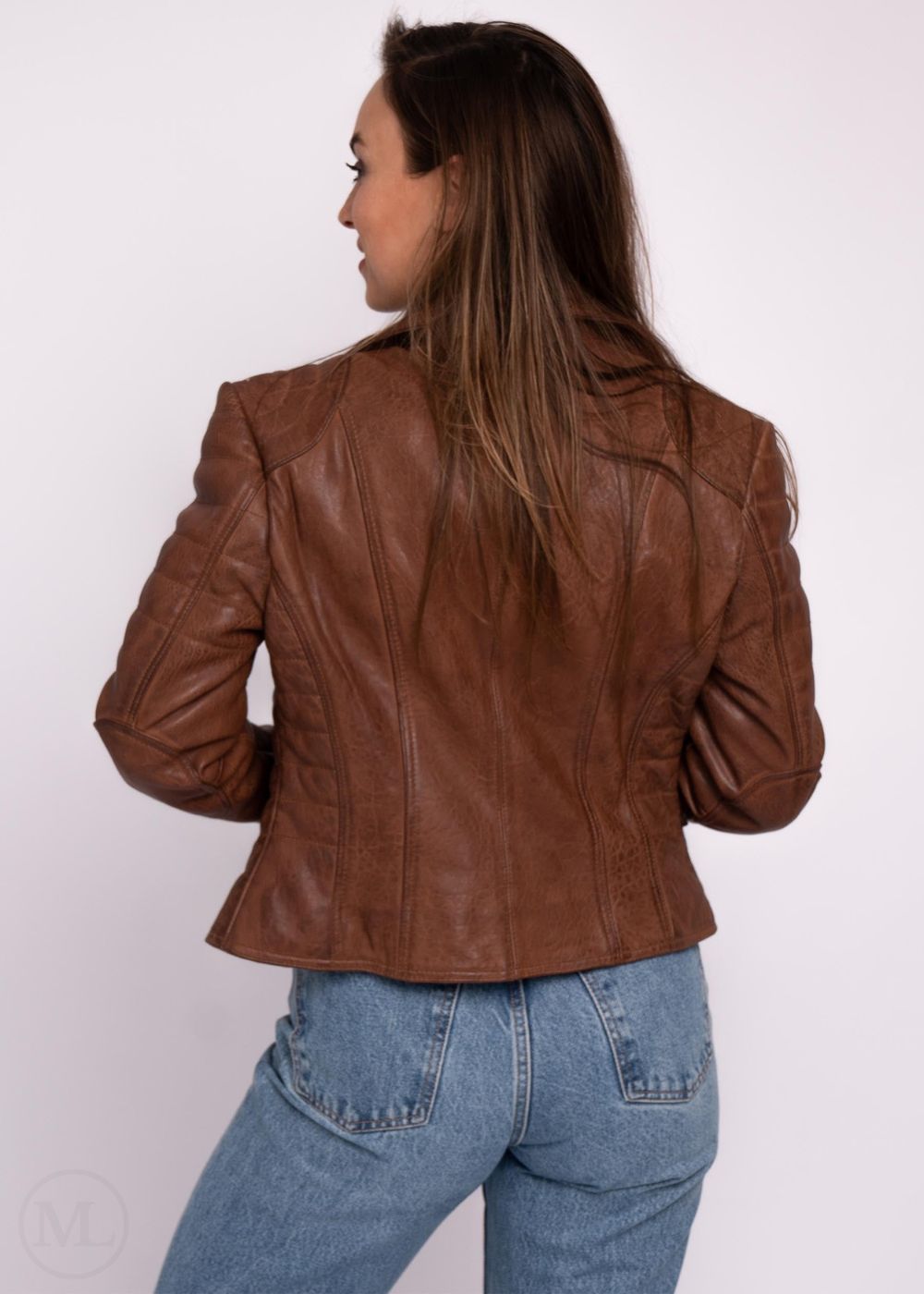 Woman wearing a cognac brown leather jacket and blue jeans on a white background