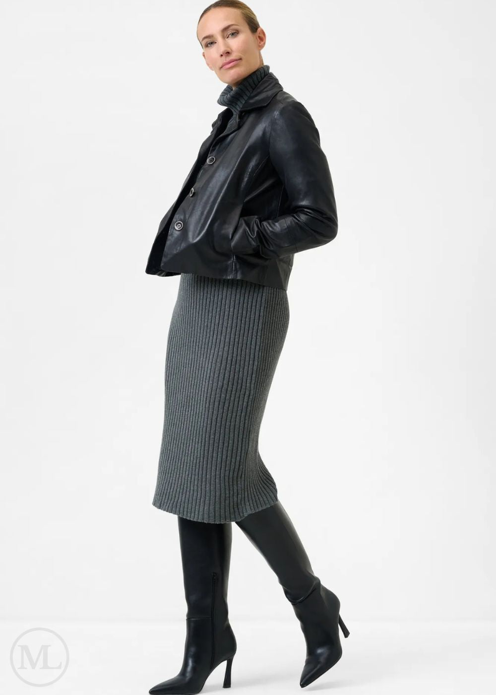 Woman wearing a black leather blazer jacket and gray ribbed skirt on a white background