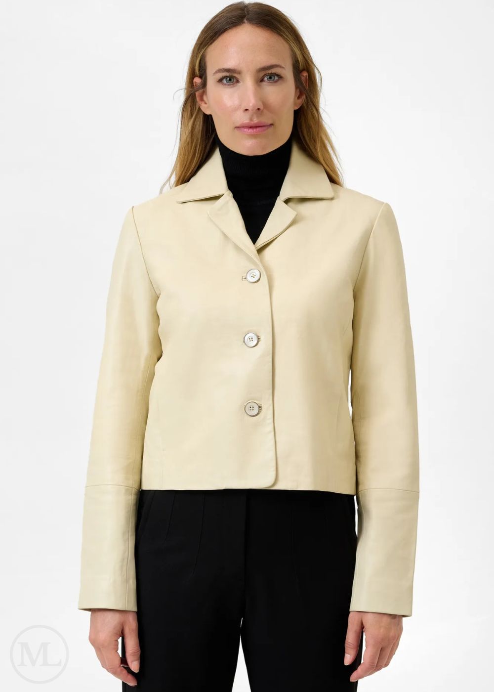 Femme portant une veste blazer en cuir ivoire sur un col roulé noir et un pantalon sur fond blanc