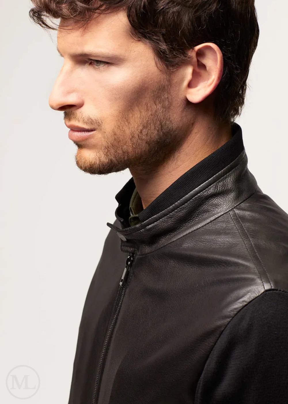 Man wearing a black leather bomber jacket on a light gray background
