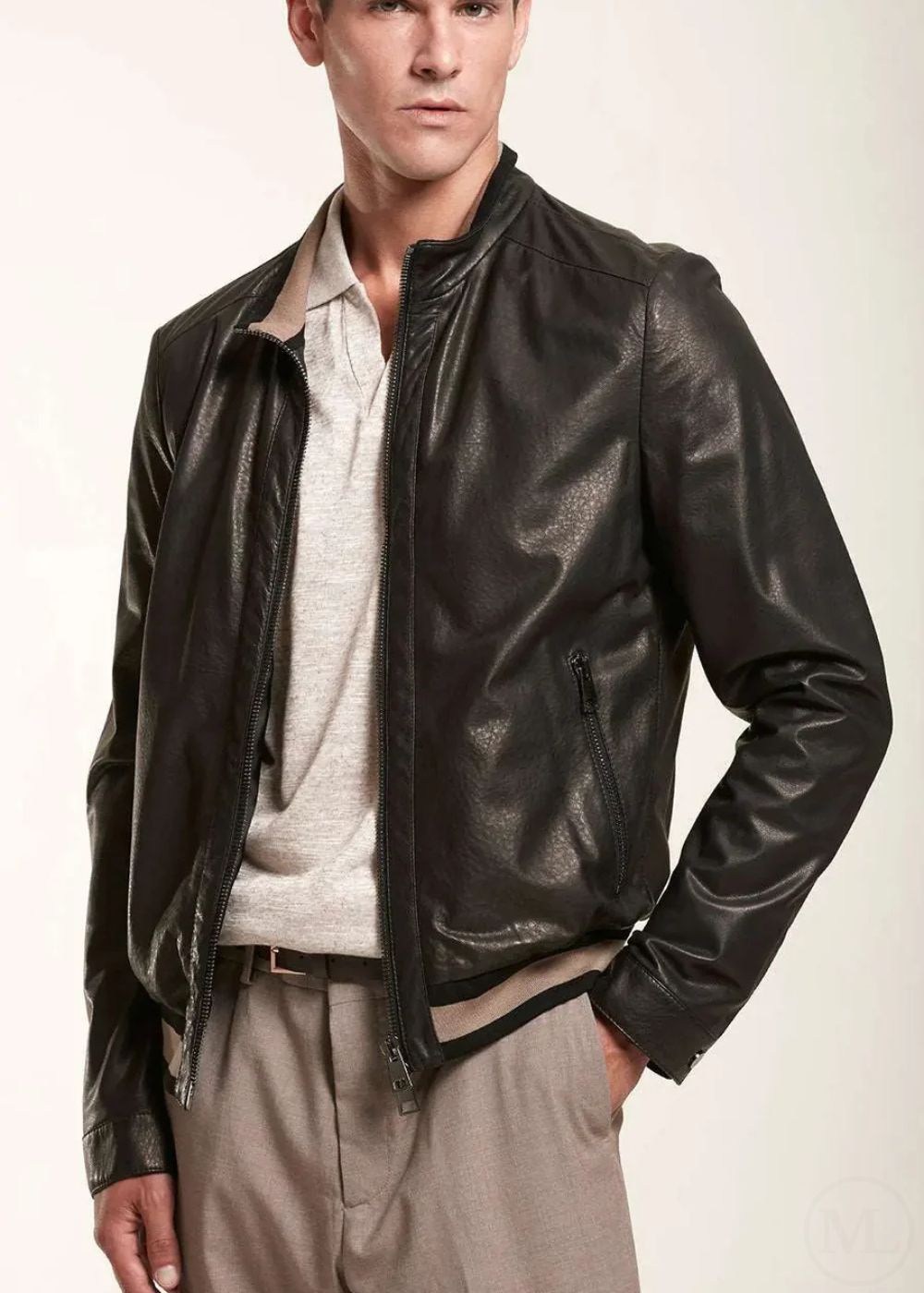 Man wearing a black leather bomber jacket over a light shirt on a white background