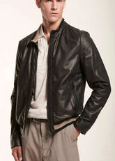 Man wearing a black leather bomber jacket over a light shirt on a white background