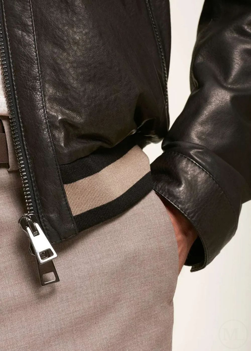 Close-up of a black leather bomber jacket with a zipper worn by a man