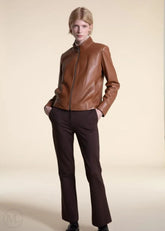 Women wearing a brown leather moto jacket and pants on a beige background