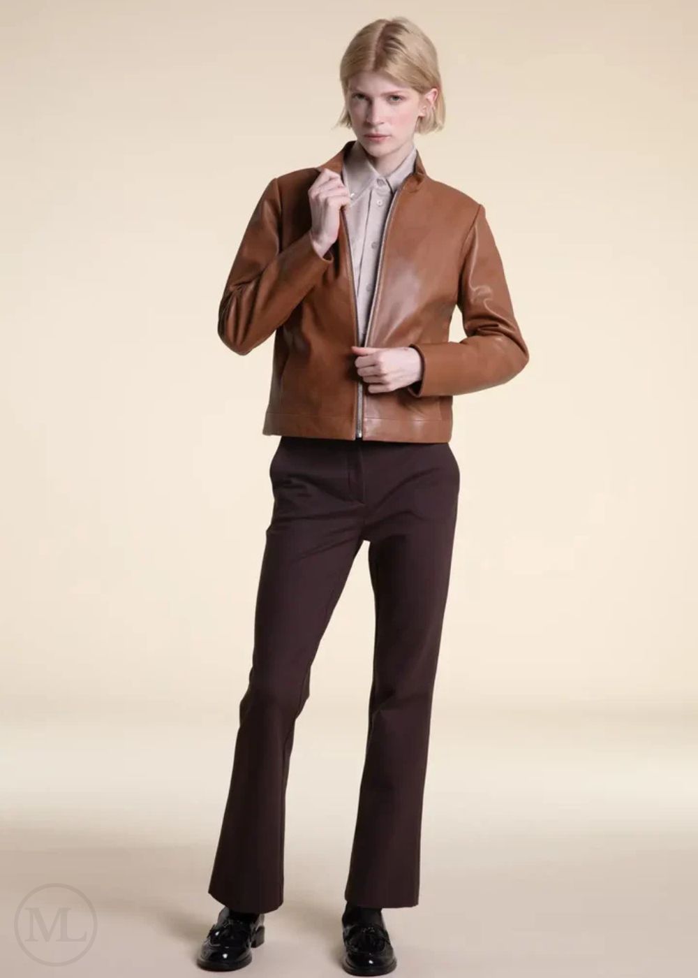 Women wearing a brown leather moto jacket and dark pants on a beige background