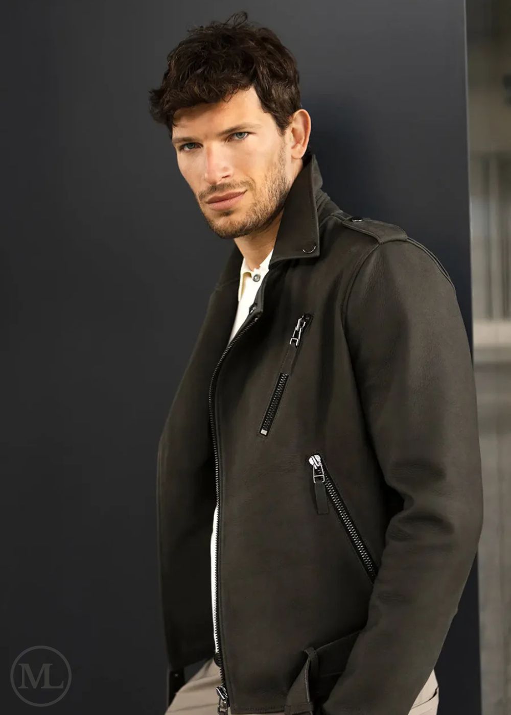 Man wearing a olive kahki leather biker jacket against a plain backgrounde