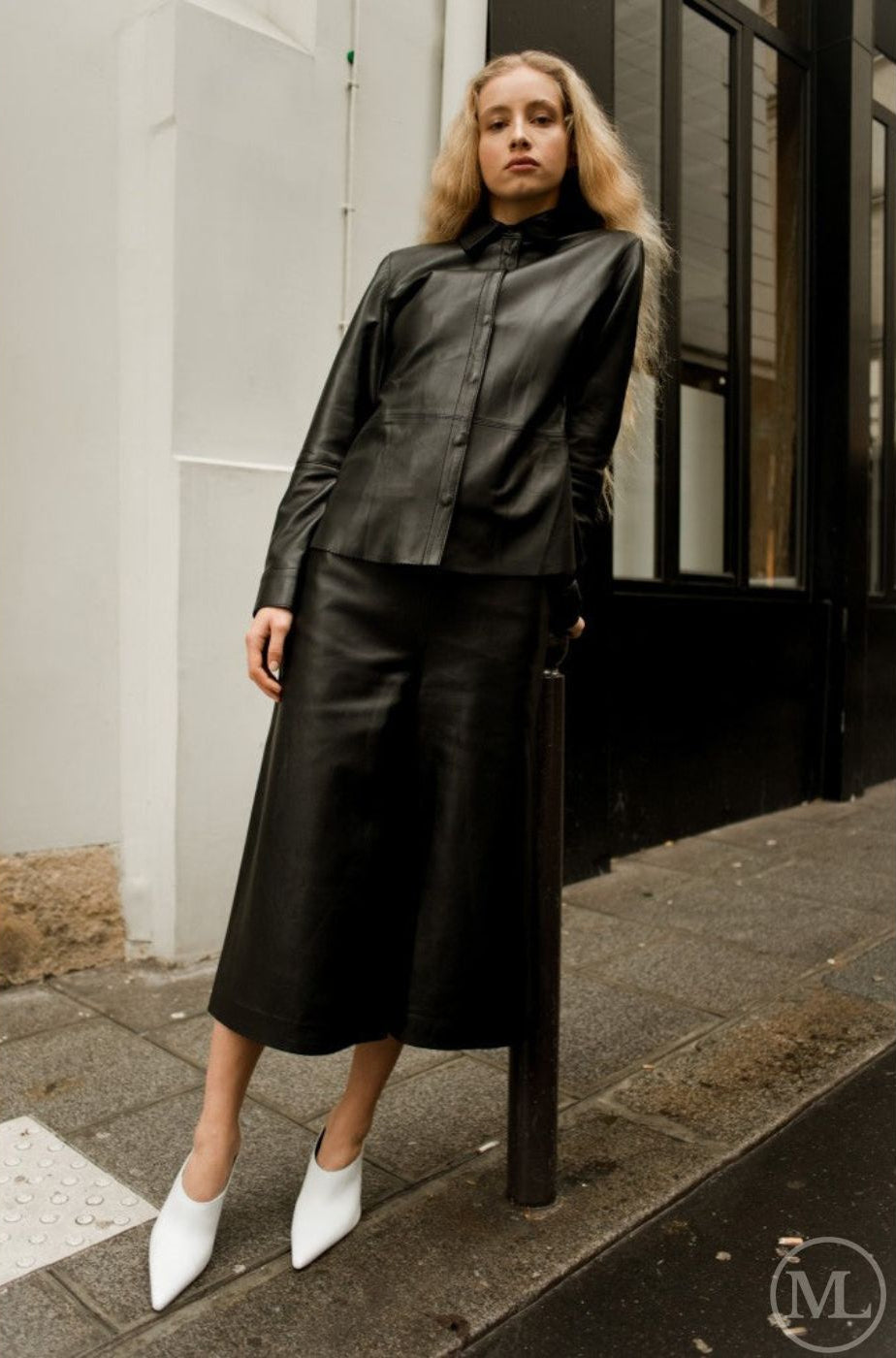 Woman wearing a black leather shirt standing on a city street.