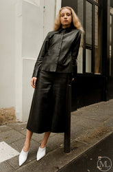 Woman wearing a black leather shirt standing on a city street.