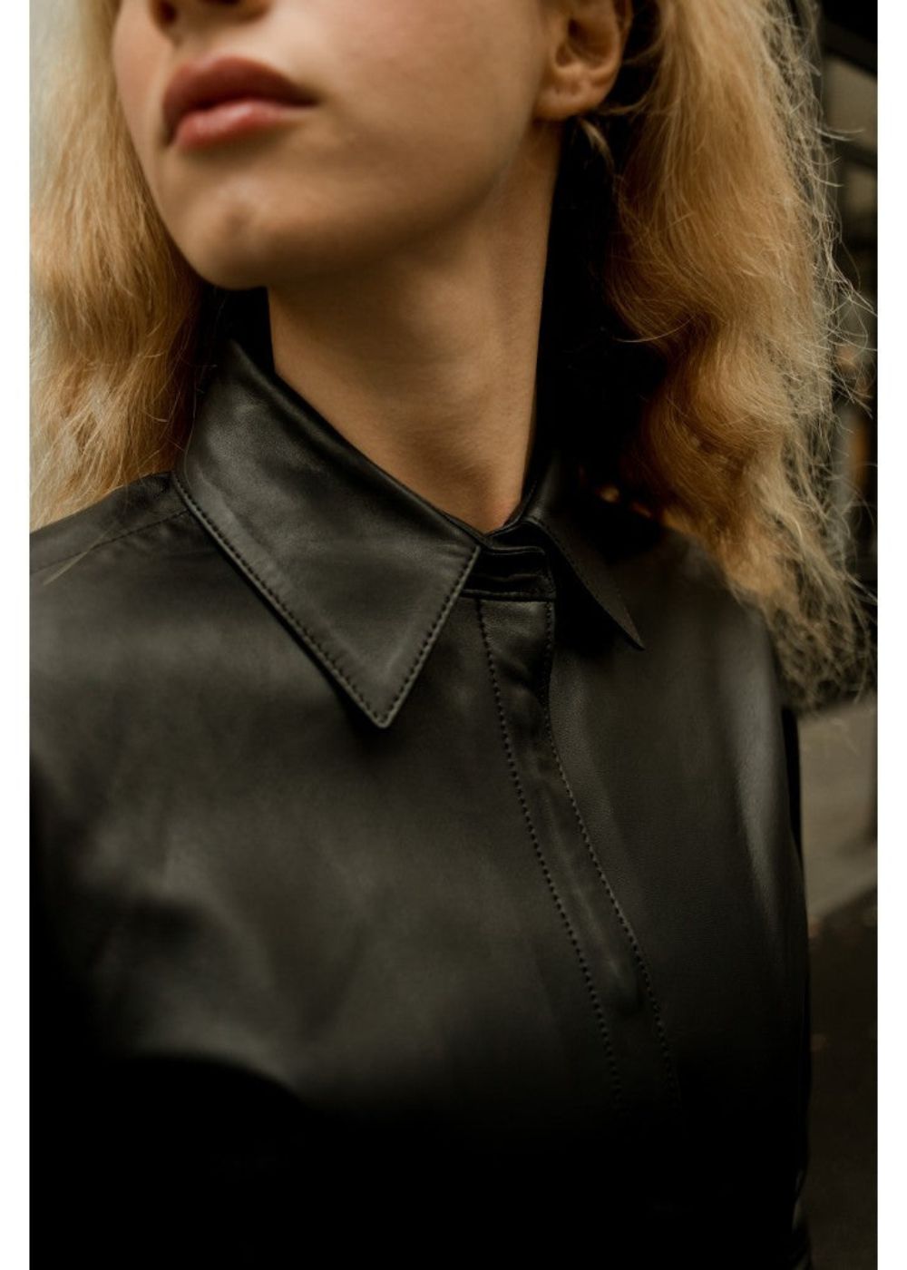 Close-up of a woman wearing a black leather shirt with a collar.