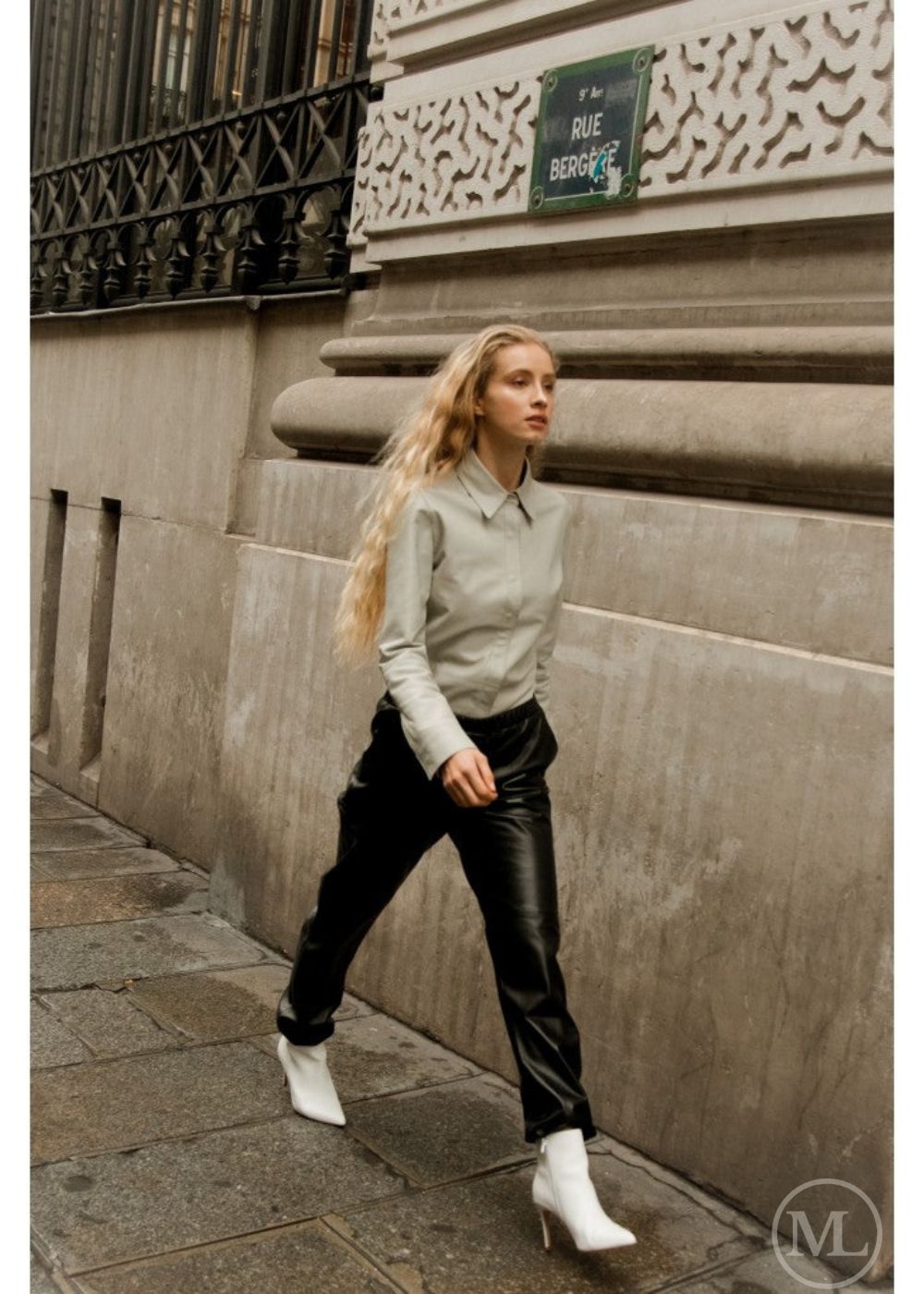 Woman wearing ivory leather shirt walking on a city street with a building in the background