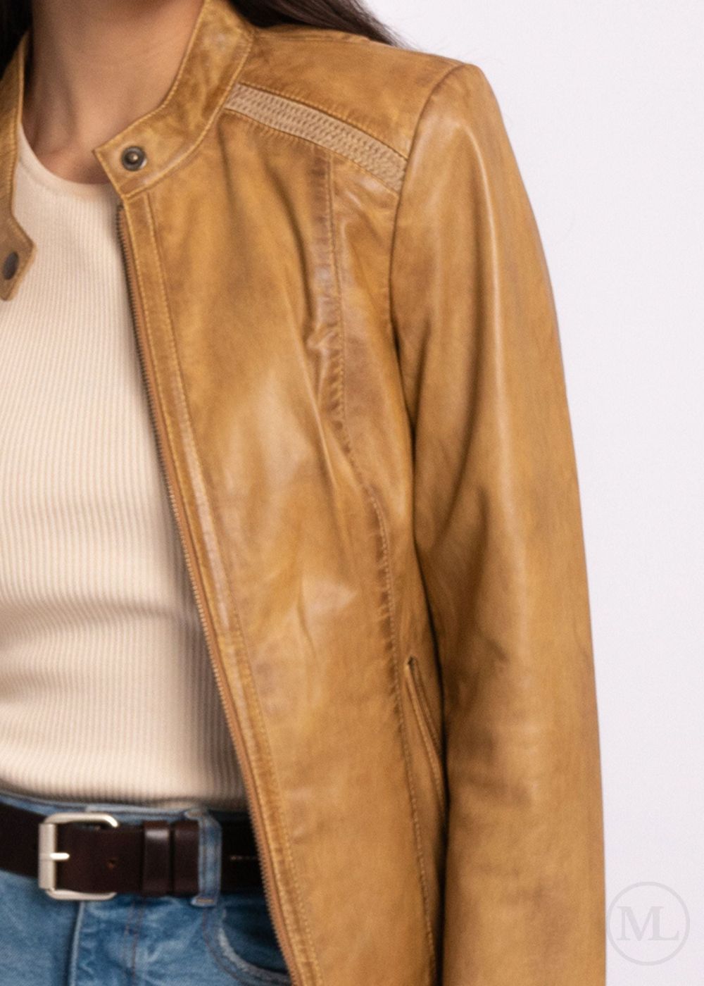 Camel leather biker jacket worn over a white shirt and blue jeans on a white background