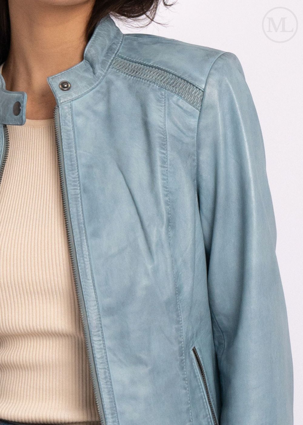 ice blue leather biker jacket worn over a beige sweater on a white background