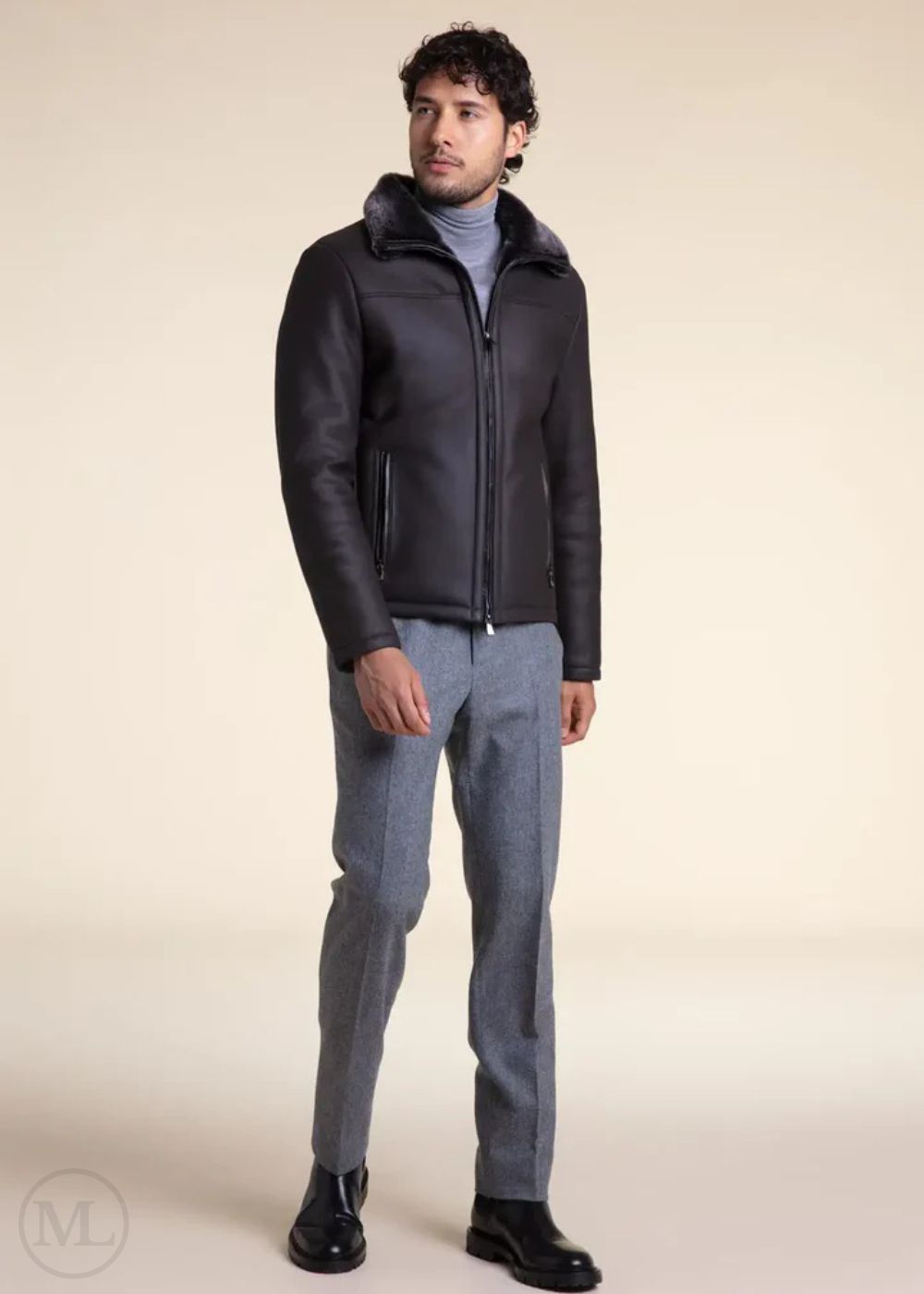 Man wearing a dark grey leather aviator jacket and gray pants on a beige background