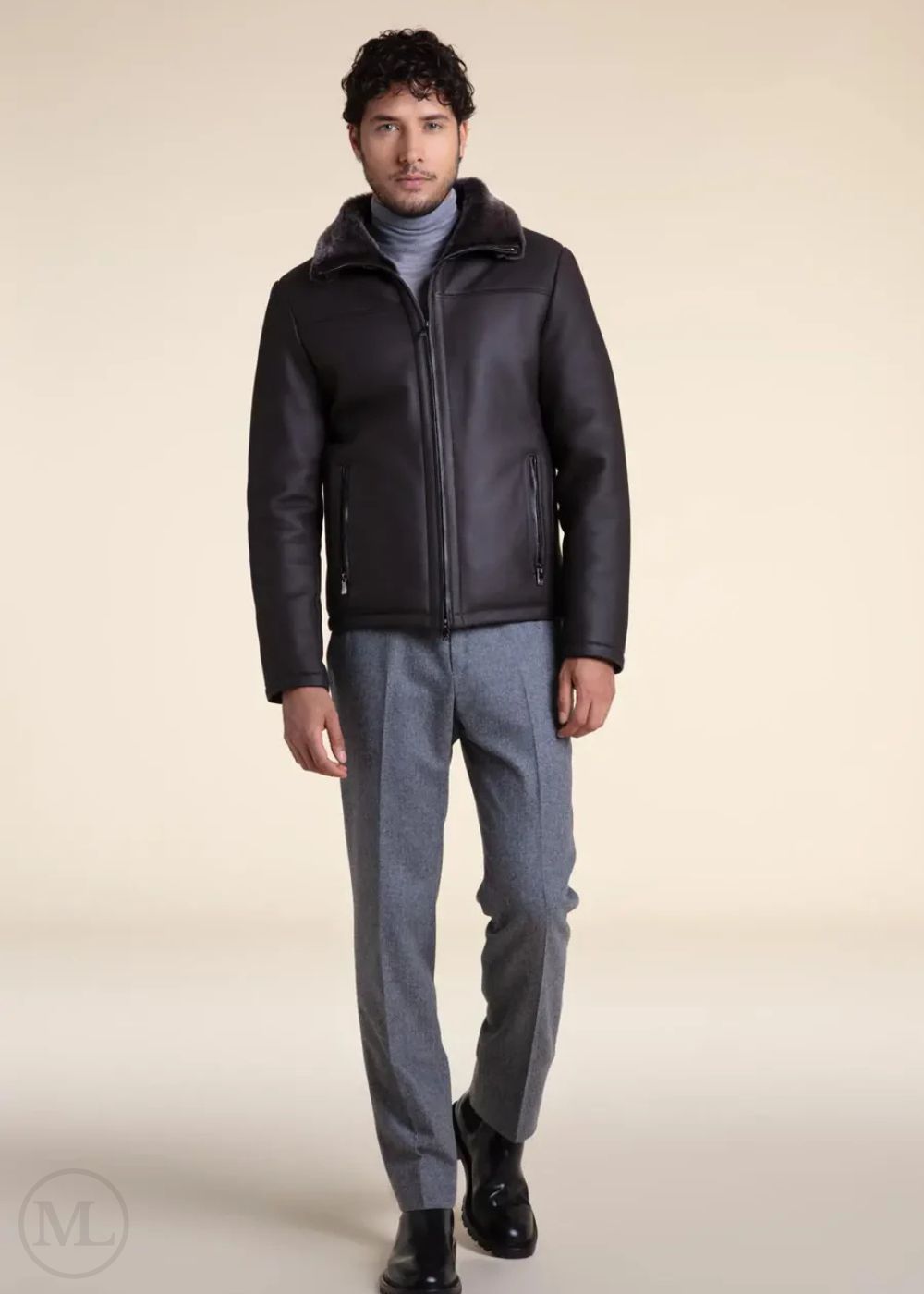 Man wearing a dark grey leather aviator jacket and gray pants on a beige background