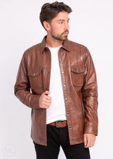 Man wearing a cognac brown leather jacket over a white shirt on a light gray background