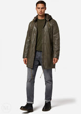 Man wearing a olive green leather coat, green shirt, and gray jeans on a white background