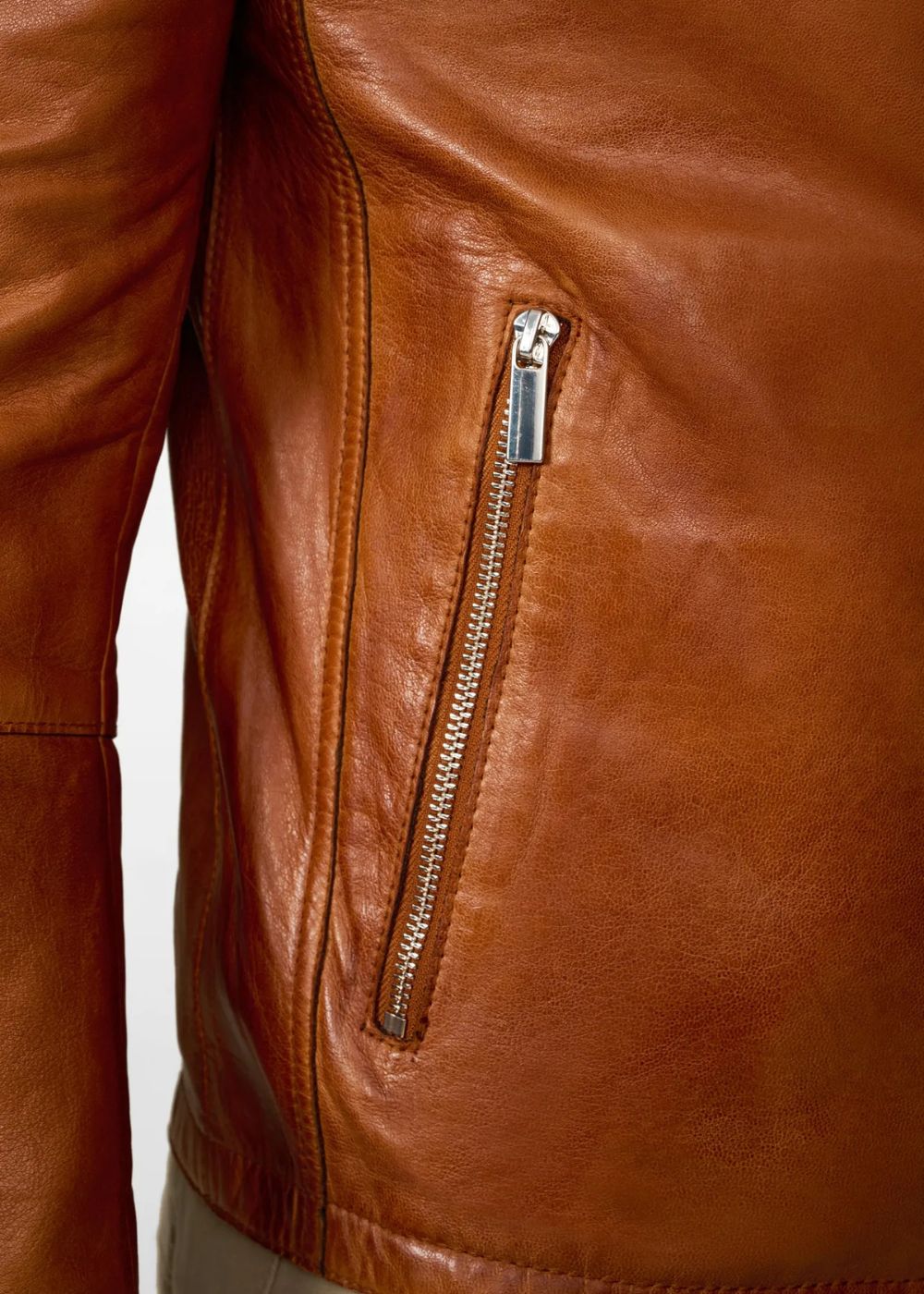 Close-up of a brown leather biker jacket with a zipper detail on a white background
