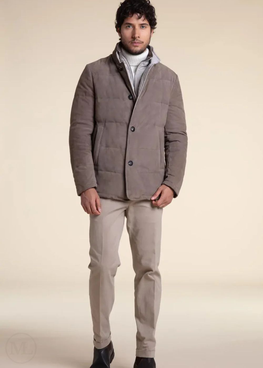 Man wearing a Camel suede leather jacket over a gray sweater with beige pants on a beige background