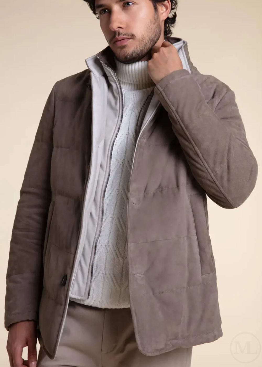 Man wearing a camel suede leather jacket over a white sweater on a beige background