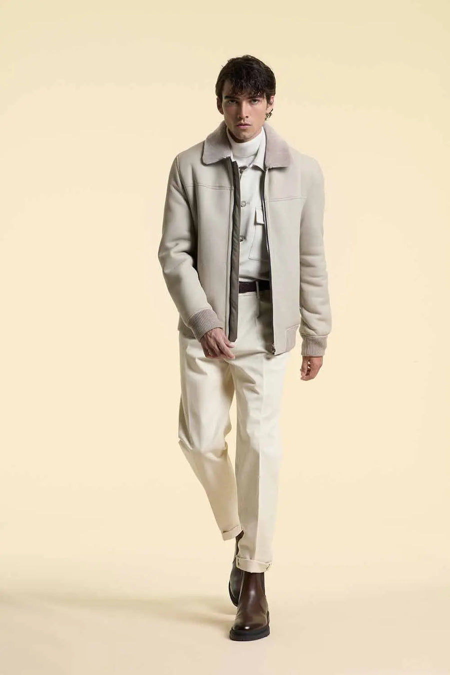 man wearing a white shearling leather jacket with old money outfit on a beige background