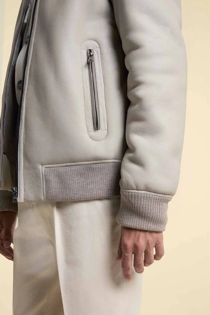 wool hems and pockets close up shot of man wearing a white shearling leather jacket on white pants