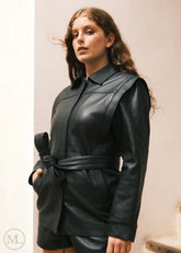 Woman wearing a black leather Coat outfit against a neutral background