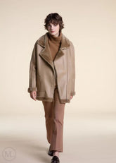 Women wearing a camel shearling leather coat with fur collar on a plain background