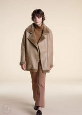 Women wearing a camel shearling leather coat with fur collar on a plain background